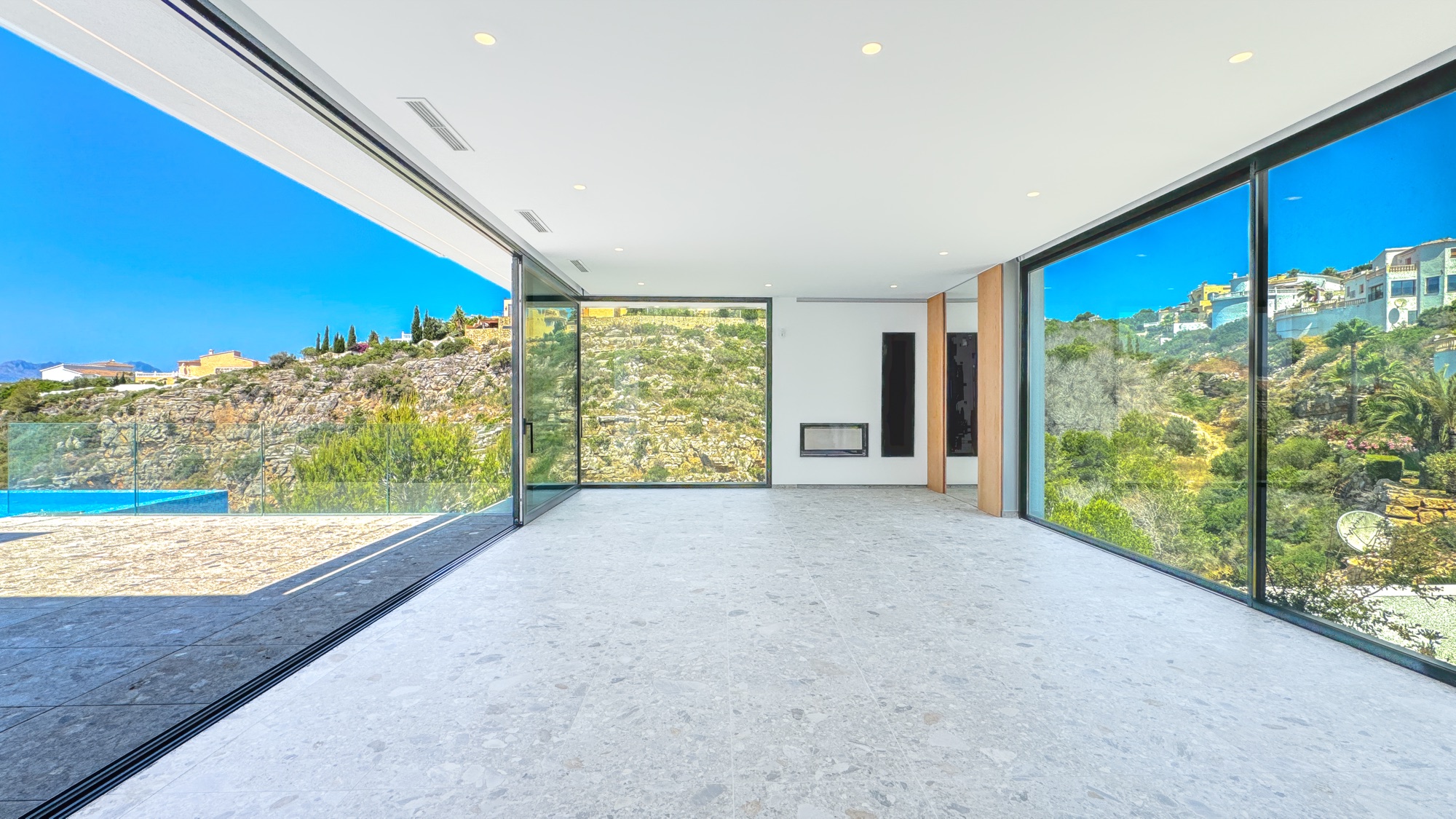 Living room with the corner glass open to the terrace and the sea
