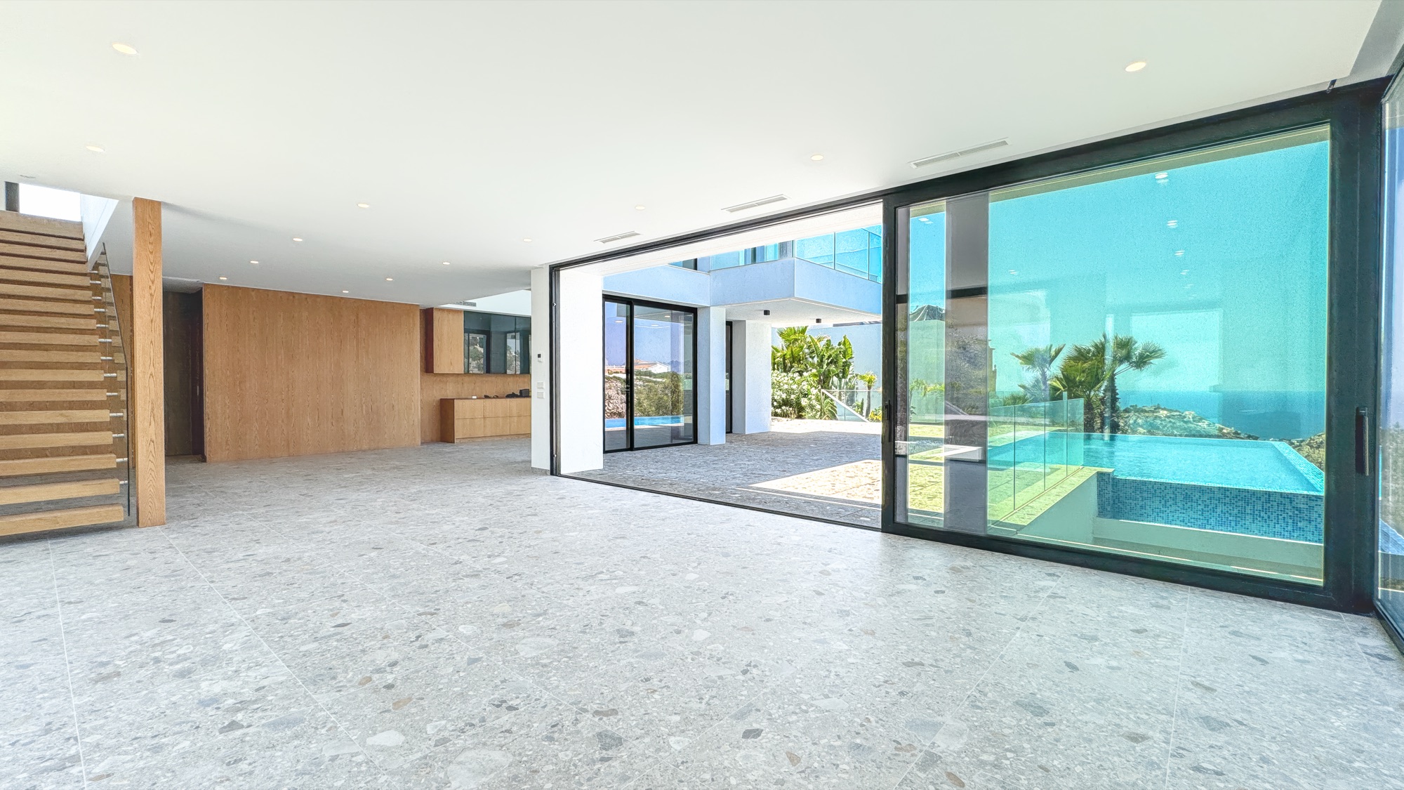 Open-plan living with the glass walls slid away to the pool terrace and the sea