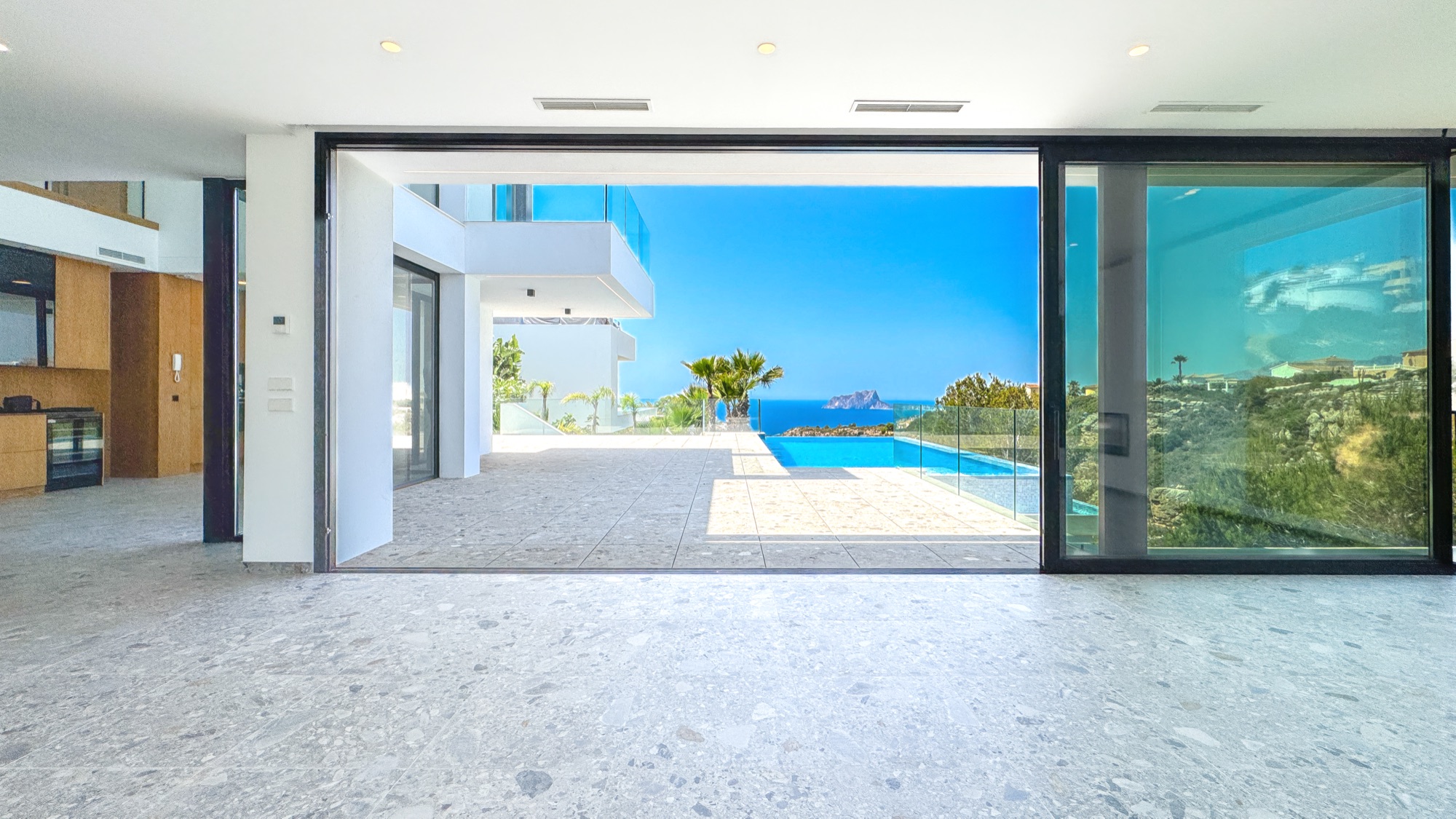 Frontal view from the salon through fully opened glass to the infinity pool and the sea