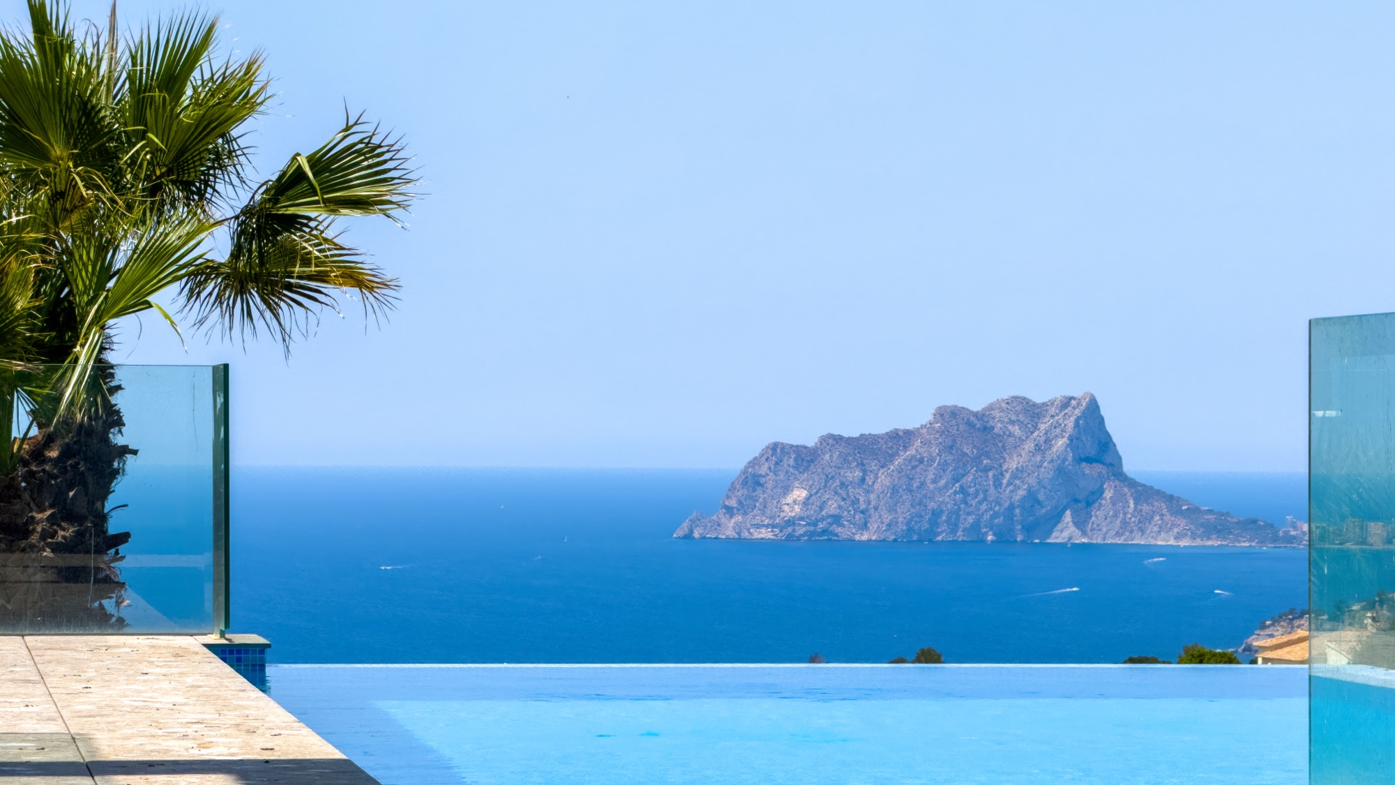Infinity pool edge with the Penon de Ifach across the water on the horizon