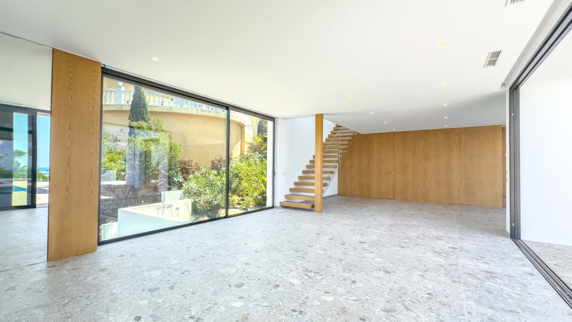Living space with oak staircase, terrazzo floor and glass walls on both sides